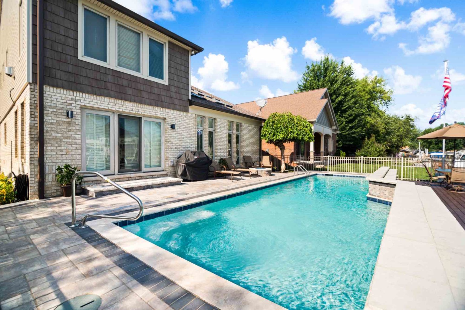 gunite pool builders Harrison twp luxury custom gunite swimming pool with jet fountains and sheet fountains Unilock pool deck design Gunite Pool Construction Custom Gunite Pool Designs Gunite Pool Installation