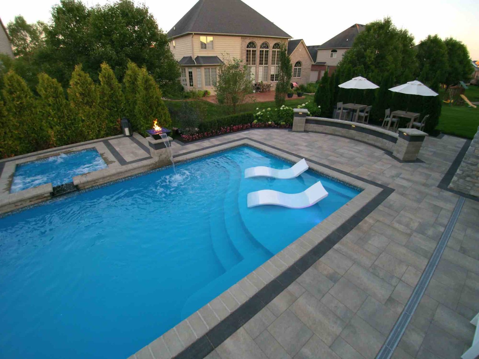 fiberglass pool designers in Shelby Twp, Mi landscape design project in Shelby Township cascade fiberglass swimming pool design with a raised spillover spa  tanning ledge sun ledge