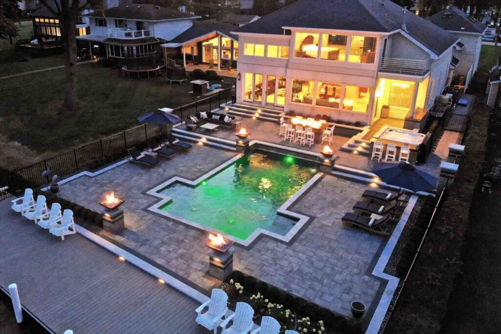 evening view of lakeside pool and patio, with pool lit green Michigan Landscape Design Landscape Design Services in Michigan Professional Landscape Design Michigan Michigan Landscape Architects Best Landscape Designers in Michigan Michigan Residential Landscape Design Custom Landscape Design Michigan Michigan Garden Design Landscape Planning Michigan Landscape Installation Michigan