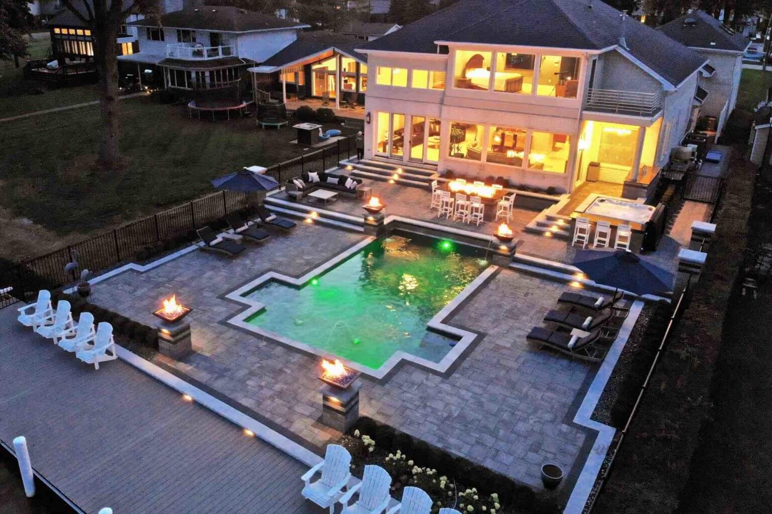 evening view of lakeside pool and patio, with pool lit green Michigan Landscape Design Landscape Design Services in Michigan Professional Landscape Design Michigan Michigan Landscape Architects Best Landscape Designers in Michigan Michigan Residential Landscape Design Custom Landscape Design Michigan Michigan Garden Design Landscape Planning Michigan Landscape Installation Michigan
