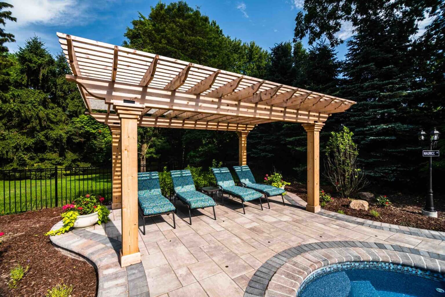covered seated area next to backyard pool outdoor luxury space michigan Pergola Designs Outdoor Pergolas Pergola Ideas Custom Pergola Construction Pergola Kits Natural Stone Pavers Michigan Michigan Paver Patio Ideas